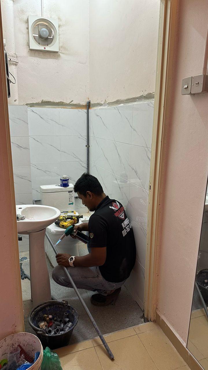 Plumber memanaskan paip PVC untuk penyambungan sanitari tandas